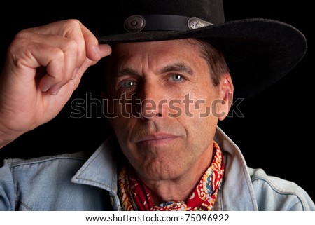 Closeup portrait of a handsome cowboy tipping his hat in salute.