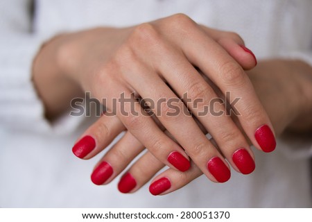 Female hands with red nails on a white background. On her nails red manicure.