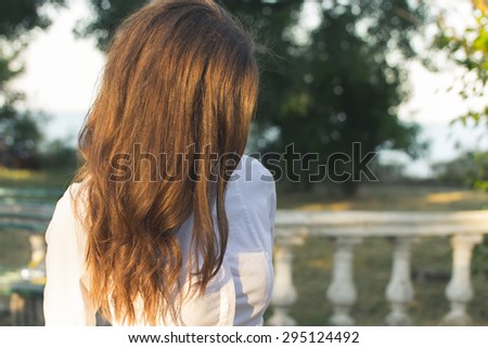 Young slender red-haired woman walking in the park sunny summer day. Outdoor activities close-up.