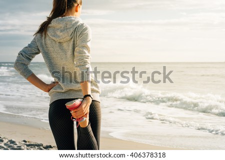 Athletic young woman engaged in morning exercises on the beach during sunrise, view from the back. The concept of a Healthy lifestyle.