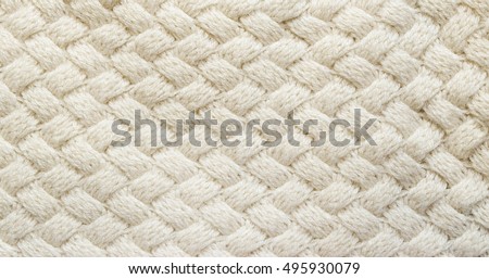 White knitted carpet closeup. Textile texture off white background. Detailed warm yarn background. Knit cashmere beige wool. Natural woolen fabric, sweater fragment.