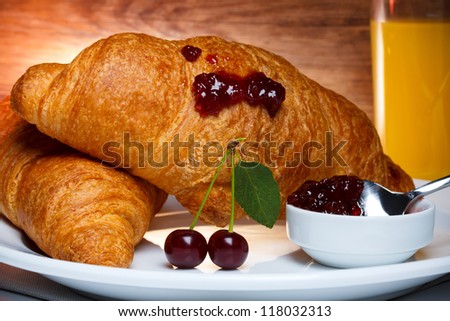 Fresh baked croissants with cherry jam and juice