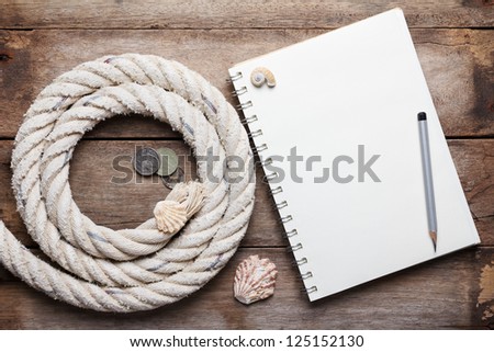Blank open notebook and sea rope with ancient coins, on wooden background
