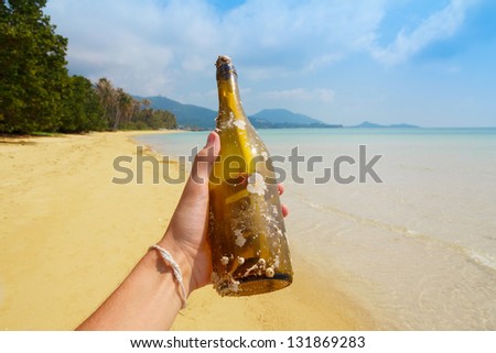 Bottle with a message in hand, on tropical island