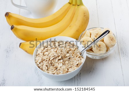 Bowl of oat flakes with sliced banana close-up on wooden table