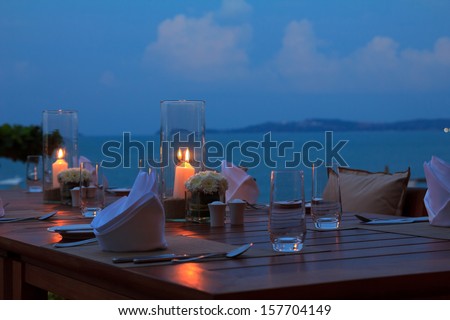 Outdoor restaurant table dinner setting on the beach at dusk