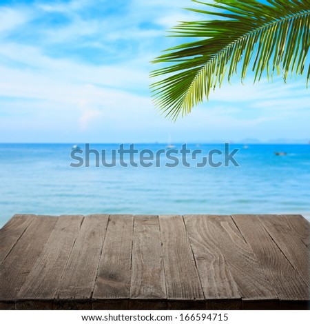 Empty wooden table with tropical sea and palm leaf on background, blank place for product