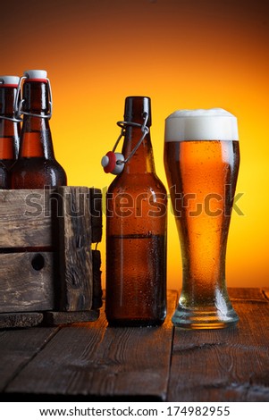 Beer glass and beer crate with bottles on wooden table still life