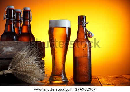 Beer glass and bottle with vintage crate and wheat bunch on wooden table