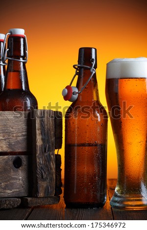 Beer glass and beer crate with bottles on wooden table still life
