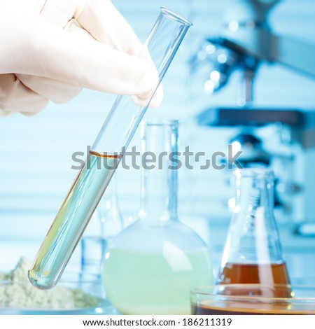 Hand in glove with test tube in laboratory, medical or chemical research concept