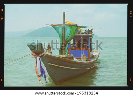 Small wooden fishing boat on tropical beach, retro film stylized