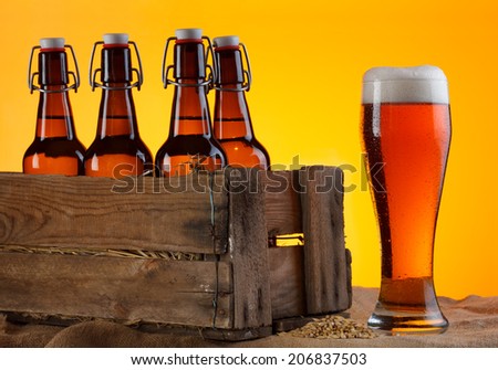 Glass of beer with bottles in crate and barley still life