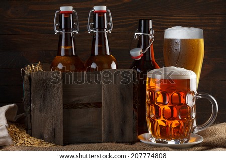 Beer glass and crate with beer bottles on burlap cloth with barley seeds