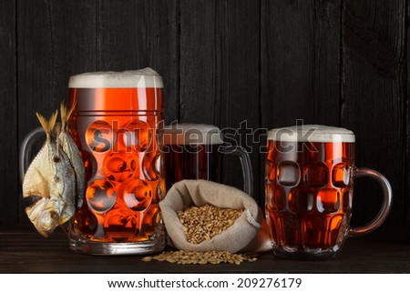Beer mug beer assortment with smoked salty fish, barley bag, dark wooden background with copy space