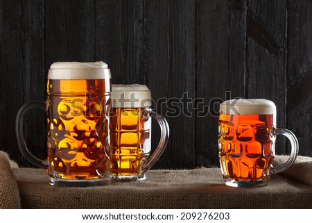 Beer glasses on table with burlap cloth, dark wooden background
