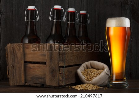 Beer glass and beer barley in bag with wooden box full of bottles on table