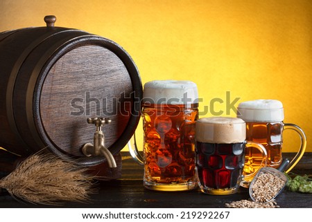 Vintage beer barrel with beer glasses on wooden table with wheat bunch and hop, still life with copy space