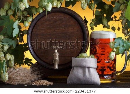 Vintage beer barrel with beer glass and fresh hops, with barley on wooden table still life
