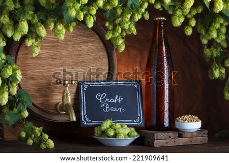 Craft bottled beer with beer barrel and fresh hops with barley for brewing still-life
