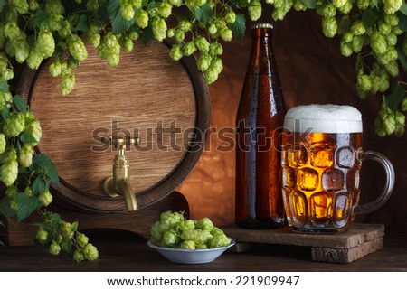 Bottled and unbottled beer with barrel and fresh hops for brewing still-life