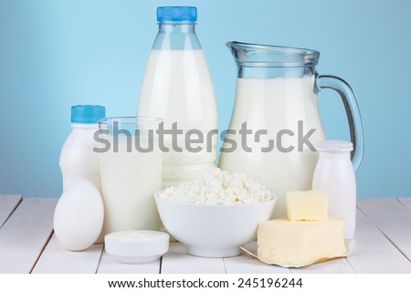 Natural organic dairy products, milk, cottage cheese, eggs, butter, yoghurt, butter and sour cream on white wooden bale and blue background still life