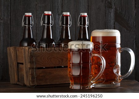 Beer glass with vintage wooden box full of beer bottles on wooden table still life