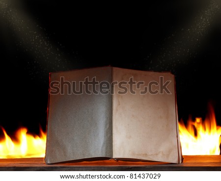 open book in ambient light with fire on background