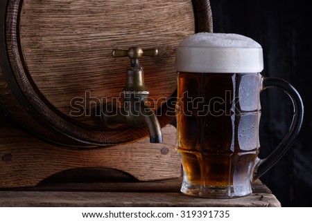 Glass of dark beer with vintage wooden beer barrel still life