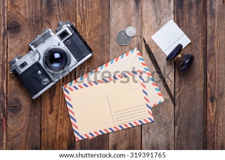 Vintage post card and envelope with retro camera on old wooden table