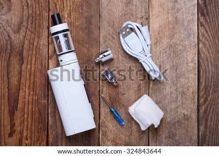 Electronic cigarette with coils, atomizer and heads on wooden table still life