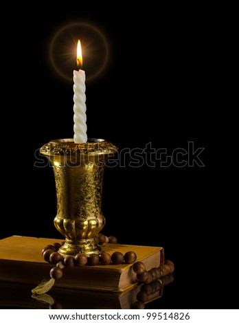 Candle with rosary and antique book