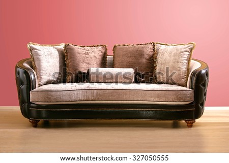 vintage couch , made of brown leather and pink velvet fabric with burgundy and pink pillow, isolated into an empty room