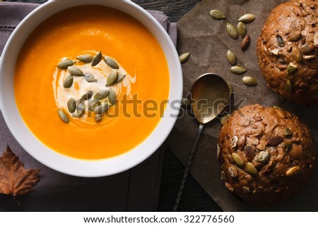 A meal with a traditional pumpkin soup and just baked rye bans with seeds. Close up top view.