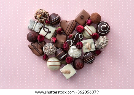 Chocolate candies and dried rose flowers heart shape composition. Sweet gift of love for St. Valentines Day.