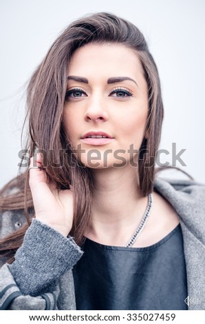young woman with long hair, beautiful makeup, leather pants, a gray sweatshirt and a leather shirt, portrait