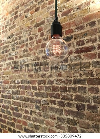 hanging light bulb filament in front of a brick wall