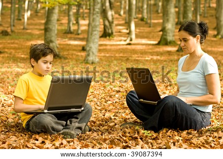 Mother and  son working on their laptops in the forest