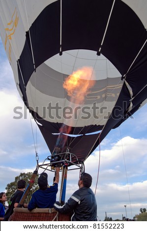 LOS CARDALES - MAY 7: The crew steadies the hot air balloon as a big flame enters the envelope. Balloon Festival. May 7, 2011 in Los Cardales, Buenos Aires, Argentina