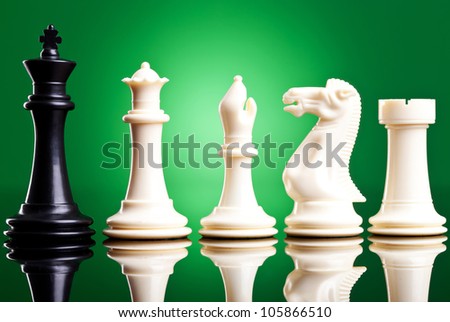 black king near white chess pieces on green background