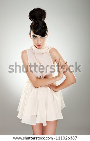 Portrait of a handsome woman model in white dress. She has a hand on her waist and the other on her opposite arm.