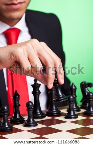business man playing chess game selective focus black makes first move. on green background