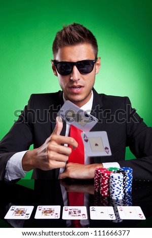 Poker player, on a green background, throwing two ace cards with full house on table