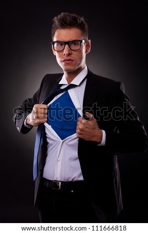 Young business man ripping off his shirt on black background