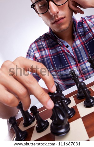 A young casual man moving his chess piece for his next move. on gray background