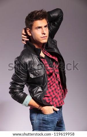 young fashion model in casual clothes and leather jacket, posing on gray background