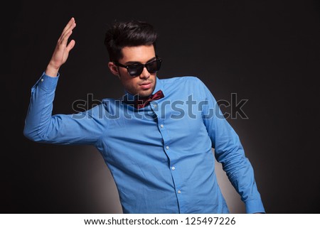 fashion man in  sunglasses and wearing bow tie with his hand in the air