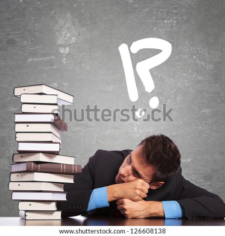tired law student looking at a big pile of books he has to learn or read to pass the exam