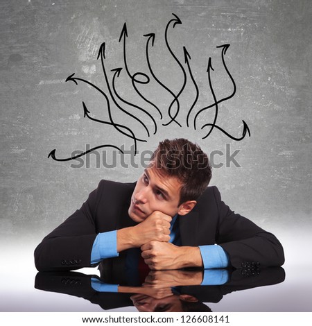 young business man sitting at his desk with his mind in all directions