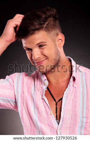 confused young casual man scratching his head and looking away from the camera, on black background